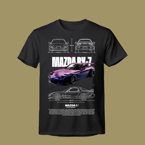 May include: A black t-shirt featuring a graphic of a purple Mazda RX-7 sports car. The design includes white line art technical drawings of the car from front, rear, and side views with measurements in mm, the text MAZDA RX-7, and a paragraph of text.