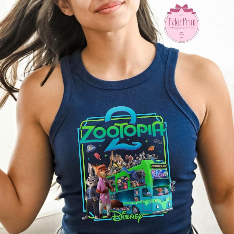 Puede incluir: Camiseta sin mangas azul marino con un gr&aacute;fico colorido de la pel&iacute;cula de Disney Zootopia. El dise&ntilde;o incluye el t&iacute;tulo de la pel&iacute;cula, personajes y un autob&uacute;s. La camiseta sin mangas es sin mangas y tiene un cuello redondo.