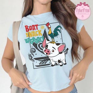 May include: Light blue t-shirt featuring a cartoon pig and rooster on a boat. The text "Boat Snack Upgrade!" is printed on the shirt.