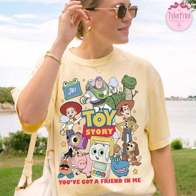 May include: Yellow t-shirt featuring a colorful graphic of Toy Story characters, including Buzz Lightyear, Woody, and Rex. The text "TOY STORY" is prominently displayed, with the phrase "YOU'VE GOT A FRIEND IN ME" at the bottom.