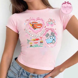 Puede incluir: Camiseta rosa de manga corta y corte corto con un gr&aacute;fico de dibujos animados de Rayo McQueen y Mate de la pel&iacute;cula Cars. El gr&aacute;fico incluye el texto "Best Day Ever" con corazones, estrellas y lazos.