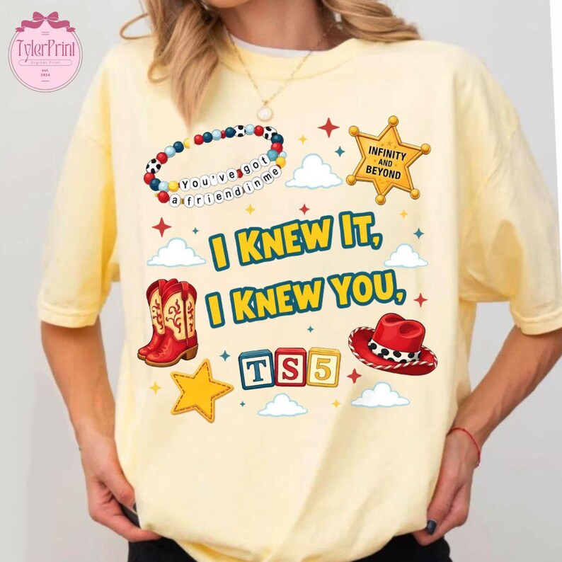 May include: A pale yellow t-shirt featuring a graphic print with a beaded bracelet, a gold sheriff star badge with the text Infinity and Beyond, red cowboy boots, a red cowboy hat, and the text I Knew It, I Knew You, and TS5 in colourful blocks.