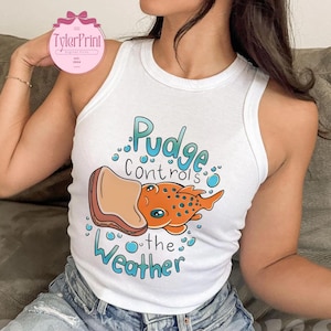 May include: White vest top featuring the text "Pudge Controls the Weather" and a cartoon illustration of an orange fish with blue eyes and a sandwich. The top is sleeveless.