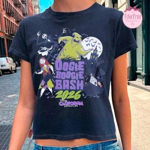 May include: A dark gray short-sleeve t-shirt featuring a graphic print of characters from The Nightmare Before Christmas. The design includes the text Oogie Boogie Bash 2026 and Disney California Adventure, with illustrations of Sally, Oogie Boogie, and Zero.