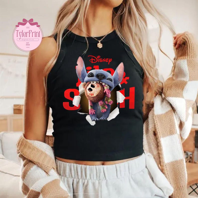 May include: Black tank top with a graphic of the Disney character Stitch. Stitch is tearing through a hole, holding a brown and pink object. The word "Disney" is above Stitch, and the word "Stitch" is in red.