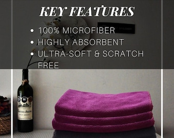 Op de afbeelding: Een stapel van drie microvezel handdoeken in paarse en grijze tinten. De afbeelding bevat de tekst "KEY FEATURES", "100% MICROFIBER", "HIGHLY ABSORBENT" en "ULTRA-SOFT & SCRATCH FREE". Een fles wijn is ook zichtbaar.
