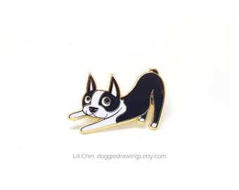 Puede incluir: Pin de esmalte de Boston Terrier negro y blanco con detalles dorados. El perro está en una pose de estiramiento con sus patas delanteras extendidas hacia adelante.