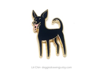 Puede incluir: Pin de perro de esmalte negro con ribete dorado. El perro tiene la lengua rosa fuera y está sonriendo. El pin está sobre un fondo blanco. El texto en la parte inferior dice "Lili Chin doggiedrawings.etsy.com".