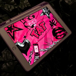 Può includere: Un tablet digitale rosa e nero con un design grafico che presenta un cuore, una catena, un telefono e la parola "TAT" in grassetto. L'ora è 5:57 sullo schermo.