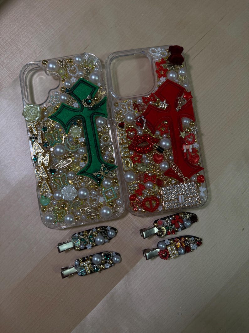 May include: Two clear phone cases decorated with rhinestones, pearls, and charms. One case features a green cross with a crown, the other a red cross. Both cases come with matching hair clips.