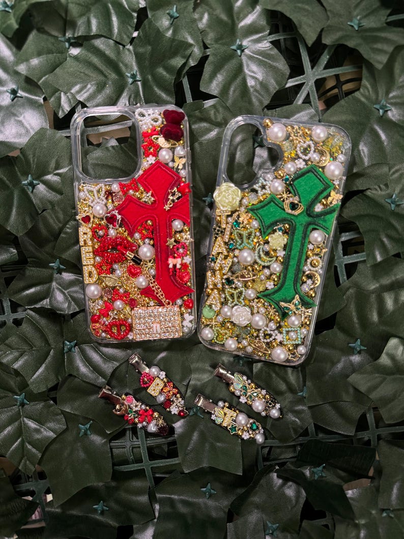 May include: Two clear phone cases with a cross design. One case has a red cross with gold and red embellishments. The other case has a green cross with gold and green embellishments. Both cases have pearls and rhinestones.