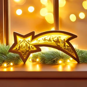 May include: A wooden star-shaped Christmas decoration with a layered design depicting the Nativity scene and the Three Wise Men. The star has a warm, yellow glow from an internal light source, and is set against a backdrop of blurred lights and greenery.