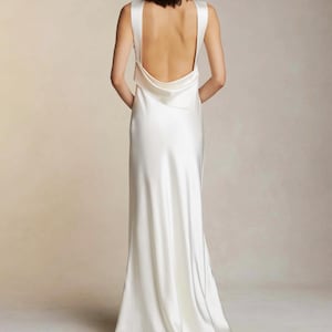Braut erhöhter Wasserfallausschnitt, schräg geschnittenes ärmelloses Seidenkleid. Offener Rücken mit drapiertem Akzentschal, Hochzeitskleid oder Kleid für den Empfang.