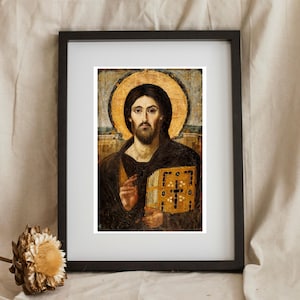 Pode incluir: &Iacute;cone religioso emoldurado com um homem com uma aur&eacute;ola, segurando um livro. A obra de arte tem uma paleta de cores douradas e castanhas, com uma moldura preta. A imagem est&aacute; sobre um fundo neutro.