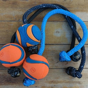 May include: Three orange and blue dog toys with ropes attached. The toys are made of rubber and have a textured surface. The ropes are black, blue, and white.