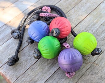 Peut inclure: Ensemble de jouets pour chiens avec des balles en caoutchouc texturé bleues, rouges, vertes, violettes et vert citron. Chaque balle est attachée à une corde noire avec une extrémité nouée. Une corde rose est également incluse.