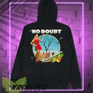 May include: Black hoodie featuring a graphic with the text "NO DOUBT BRAND" above a circular image. The image depicts a woman in a red dress, a barren tree, and the words "Tropic Kingdom".