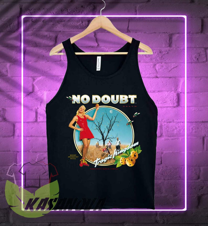 May include: Black tank top featuring the band name "NO DOUBT" in white text. The shirt has a circular graphic with a woman in a red dress, a tree, and the words "Tragic Kingdom". The tank top is hanging on a wooden hanger.