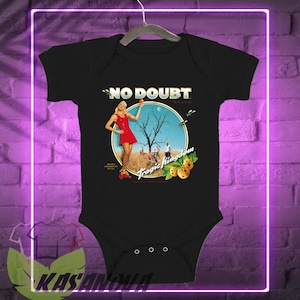 May include: Black baby bodysuit featuring the words "NO DOUBT" above a circular graphic. The graphic depicts a woman in a red dress, a barren tree, and the words "Tragic Kingdom". The bodysuit has three snaps at the bottom.
