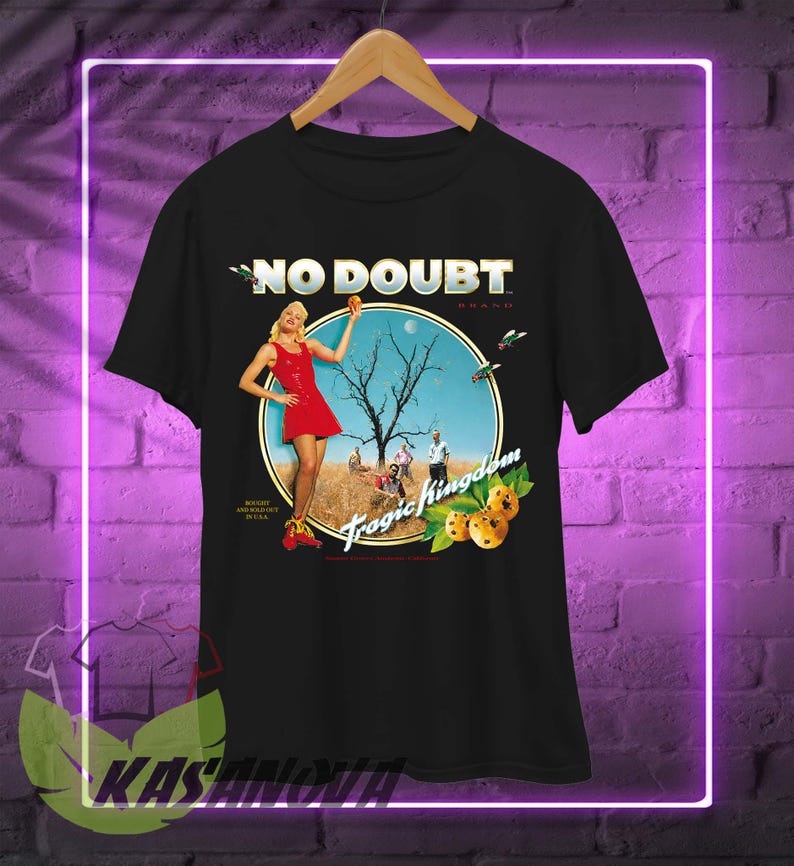 May include: Black t-shirt featuring the words "NO DOUBT" in gold lettering above a circular graphic. The graphic includes a woman in a red dress, a tree, and the words "Tragic Kingdom".