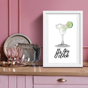 May include: White framed print with a drawing of a margarita cocktail with a lime wedge. The text below the image reads "It's Gin O'clock".