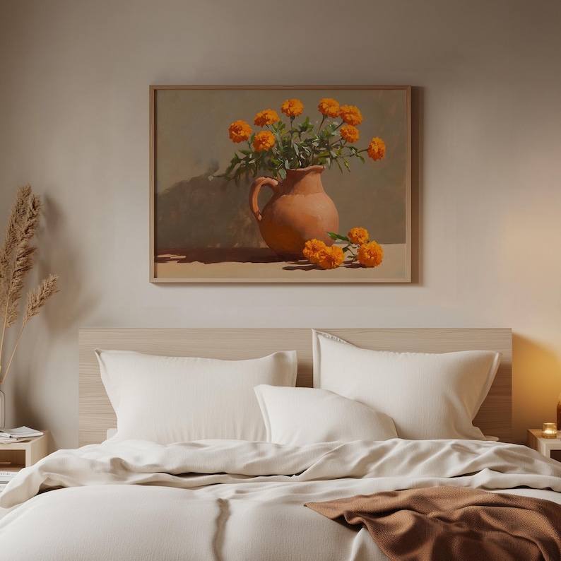 May include: A framed painting of orange marigold flowers in a terracotta pitcher. The artwork is displayed above a bed with white bedding and a brown blanket. The room has a neutral color palette.