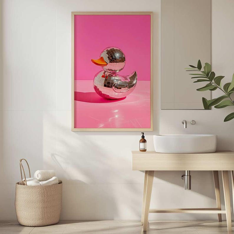 Puede incluir: Un pato de goma plateado con forma de bola de discoteca sobre un fondo rosa. El pato est&aacute; sentado sobre una superficie rosa y refleja la luz.