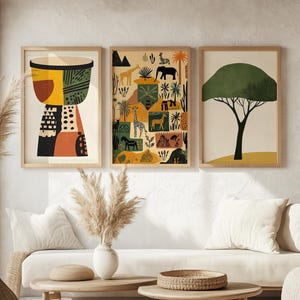 May include: Three framed prints with a safari theme. The first print features a stylised drum with geometric patterns in shades of brown, yellow, and orange. The second print features a colourful illustration of giraffes, zebras, and other animals in a desert landscape. The third print features a stylised green tree with a brown trunk against a beige background.