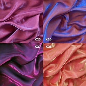 May include: A grid of four fabric swatches with a shimmering, iridescent finish. Top left K25 is deep magenta, top right K26 is vibrant blue-purple, bottom left K27 is dark violet, and bottom right K28 is a warm coral-peach with gold highlights.