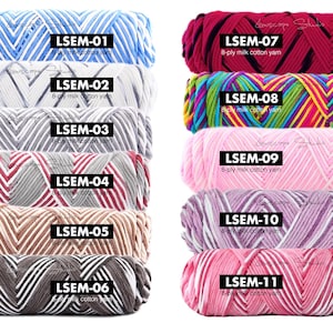 May include: A collection of eleven skeins of 8-ply milk cotton yarn in various colors. Each skein is labeled with a unique LSEM number. Colors include blue, white, gray, red, brown, and pink, with some skeins featuring striped patterns.