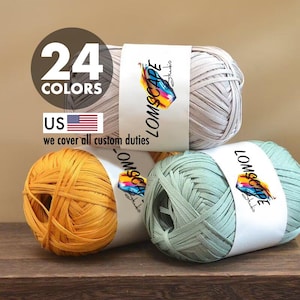 Può includere: Tre gomitoli di filato nei colori neutro, giallo e verde acqua. Ogni gomitolo ha un'etichetta bianca con il testo "LOMSCAPE Studio" e un design colorato. L'immagine include anche il testo "24 COLORS" e una bandiera americana.