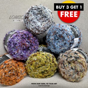 May include: Six skeins of colorful boucle yarn in various shades of blue, purple, brown, orange, and yellow. The yarn is arranged in a pyramid shape. The text "BUY 3 GET 1 FREE" is displayed in a red circle at the top of the image. The text "FROM OUR YARN, TO YOUR ART create by lomscape" is displayed at the bottom of the image.
