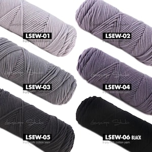 May include: A collection of six skeins of 8-ply milk cotton yarn in various shades of gray, purple, and black. Each skein is labeled with a unique code: LSEW-01, LSEW-02, LSEW-03, LSEW-04, LSEW-05, and LSEW-06 BLACK. The yarn is tightly wound, suggesting it's ready for knitting or crochet projects.