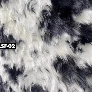May include: Close-up of a faux fur fabric with a pattern of black and white stripes. The long, shaggy fibers create a textured surface. The text "LSF-02" is in a black rectangle in the lower left corner.