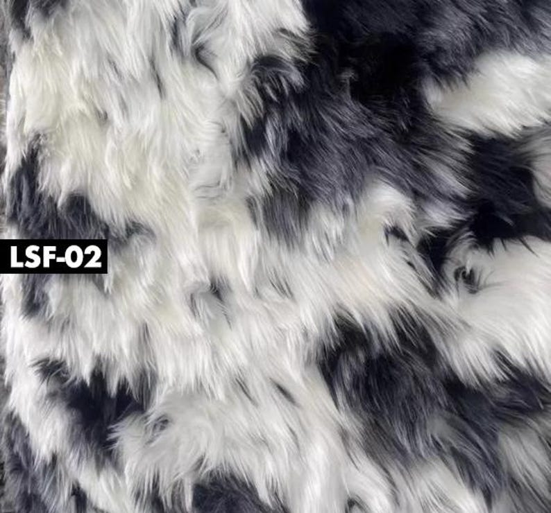 May include: Close-up of a faux fur fabric with a pattern of black and white stripes. The long, shaggy fibers create a textured surface. The text "LSF-02" is in a black rectangle in the lower left corner.