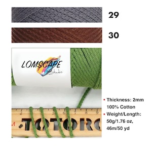 May include: Image of three yarn skeins in gray, brown, and green. The green yarn is measured with a wooden ruler. The label reads "LOMSCAPE Studio". The text on the right indicates the yarn is 2mm thick, 100% cotton, and 50g/1.76 oz, 46m/50 yd.