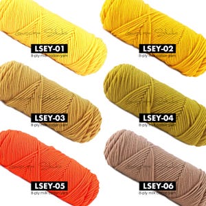 May include: A collection of six skeins of 8-ply milk cotton yarn in various colors. The colors include yellow, mustard, orange, olive green, and brown. Each skein is labeled with a code: LSEY-01, LSEY-02, LSEY-03, LSEY-04, LSEY-05, and LSEY-06.