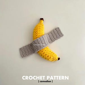 May include: A crocheted banana with a grey crocheted headband. The banana is yellow with a brown tip. The headband is grey and is wrapped around the banana. The text "CROCHET PATTERN [comedian]" is at the bottom.