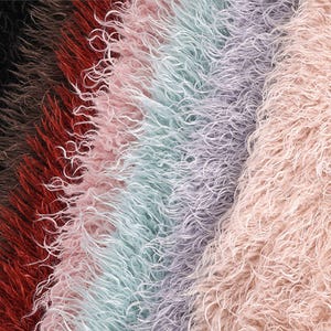 May include: A collection of long-pile faux fur fabric strips arranged in a vertical gradient. The colors transition from black and dark brown to deep red, soft pink, light mint green, pale lavender, and a final section of light beige.