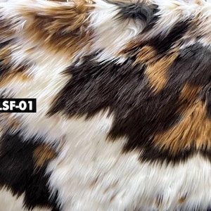 May include: Close-up of faux fur fabric with a pattern of white, brown, black, and tan. The fabric has long, shaggy fibers. The text "LSF-01" is in a black rectangle in the lower left corner.