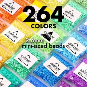 Puede incluir: Una colección de 264 colores de mini cuentas de 2,6 mm, empaquetadas en bolsas de plástico transparente. Las bolsas están etiquetadas con la marca "Lomscape" y códigos de color. Las cuentas son de varios colores, incluyendo naranja, amarillo, verde y azul.