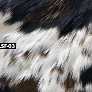May include: Close-up of faux fur fabric with a mix of black, white, and brown colors. The long, shaggy fibers create a textured appearance. The text "LSF-03" is in a white box in the corner.