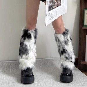 May include: Black platform boots with faux fur leg warmers in a black, white, and gray pattern. The leg warmers are fluffy and cover the lower legs, creating a bold, stylish look.