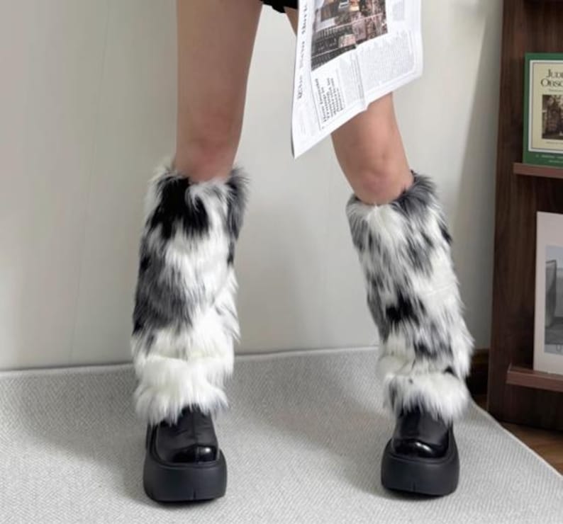 May include: Black platform boots with faux fur leg warmers in a black, white, and gray pattern. The leg warmers are fluffy and cover the lower legs, creating a bold, stylish look.