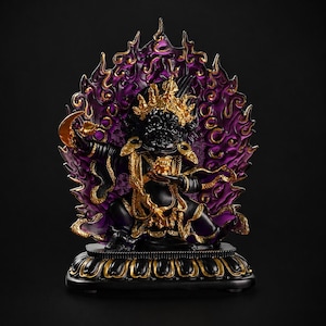 Puede incluir: Una estatua negra y dorada de una deidad con expresión feroz, que sostiene una luna creciente y un pequeño recipiente. La figura está rodeada por un halo translúcido de color púrpura en forma de llama y se asienta sobre una base de loto.