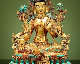 May include: A golden statue of a seated deity, adorned with a jeweled crown and turquoise accents. The figure has a serene expression and is richly detailed with intricate patterns and embellishments. The statue is set against a green backdrop.