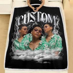 May include: Black blanket with the word "CUSTOM" in white script. The blanket features a photo of a person wearing sunglasses and a green and white patterned shirt. Lightning bolts and clouds are also in the design.