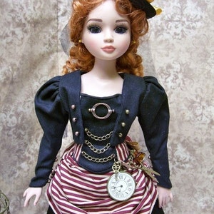 Puede incluir: Una muñeca de porcelana con cabello rojo que lleva un vestido a rayas blancas y negras, una chaqueta negra con detalles dorados y un sombrero de copa negro con una cinta dorada. La muñeca sostiene un reloj de bolsillo con una cadena.