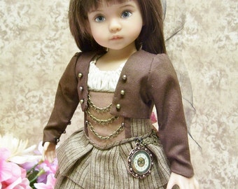 May include: A doll wearing a brown jacket with gold buttons and a brown and white striped skirt. The doll has a black hat with a veil and a pocket watch pendant.