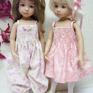 May include: Two dolls wearing floral print dresses. The doll on the left is wearing a white dress with pink flowers and has brown hair. The doll on the right is wearing a pink dress with white flowers and has blonde hair.